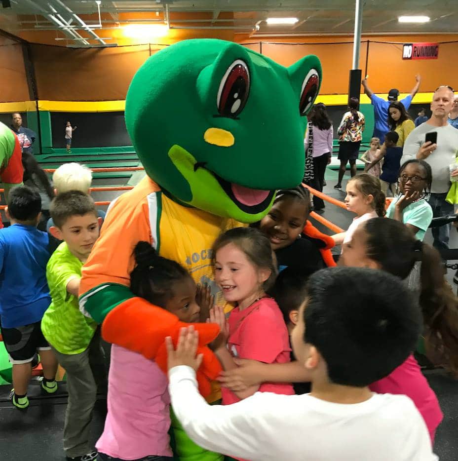 Rockin‘ Jump Trampoline Parks Indoor playground frog mascot hugging children at trampoline park